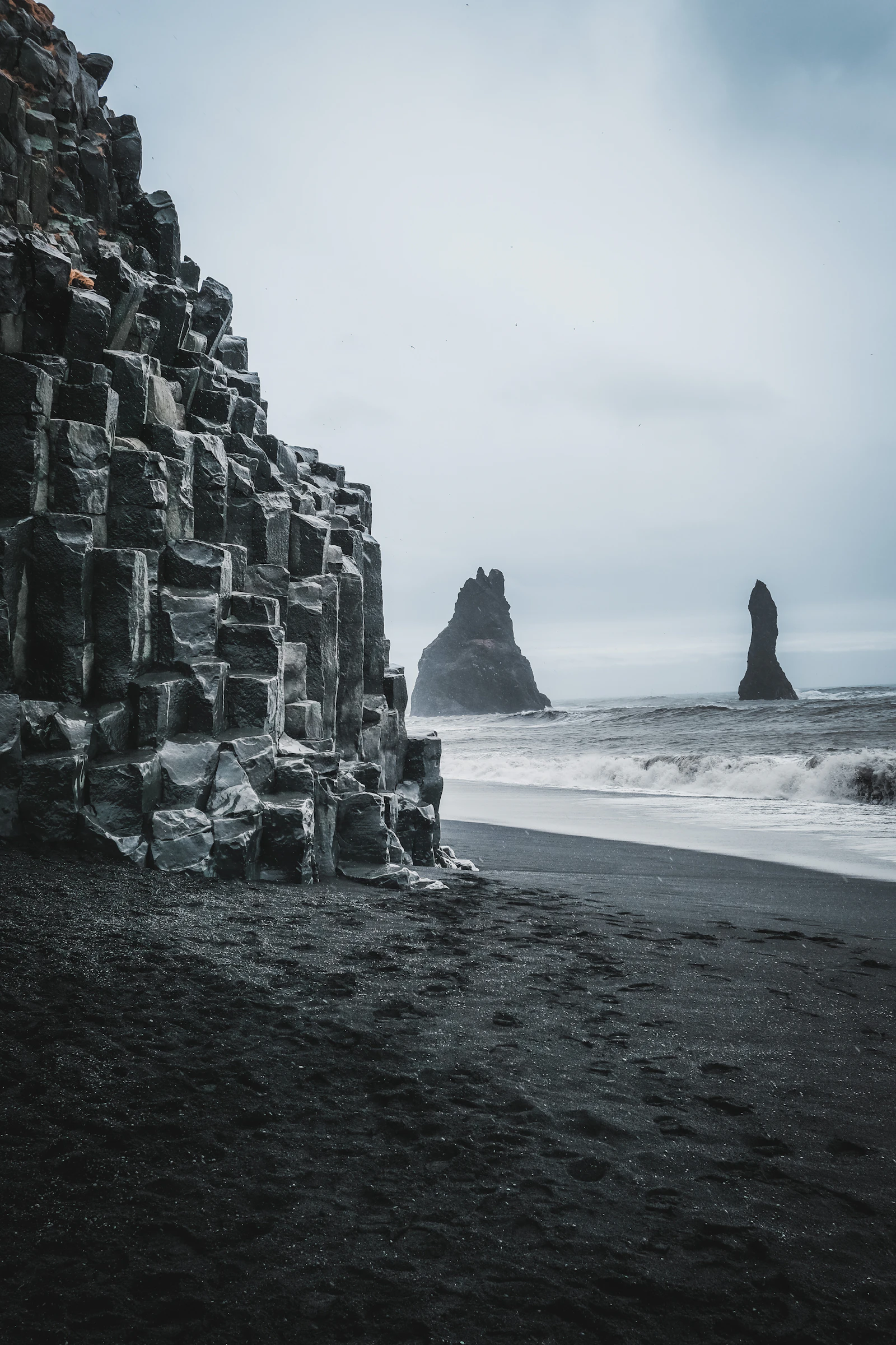 Reynisfjara black sand beach with basalt columns, black sand, waves, and Reynisdrangar sea stacks