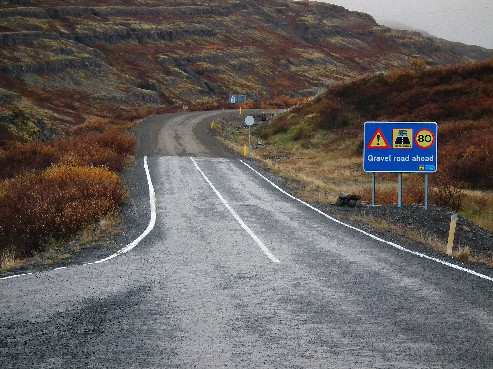 A road sign marking the end of tarmac and the gravel road ahead on Iceland's Route 60