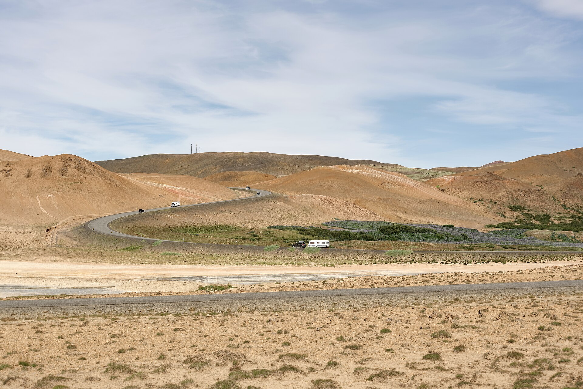 Route 1 near Hverarönd crossing rolling volcanic terrain, with cars and campervans on the road