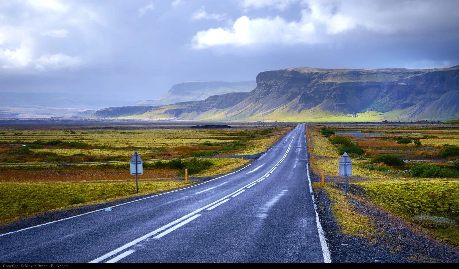 A wet Iceland road and distant mountains