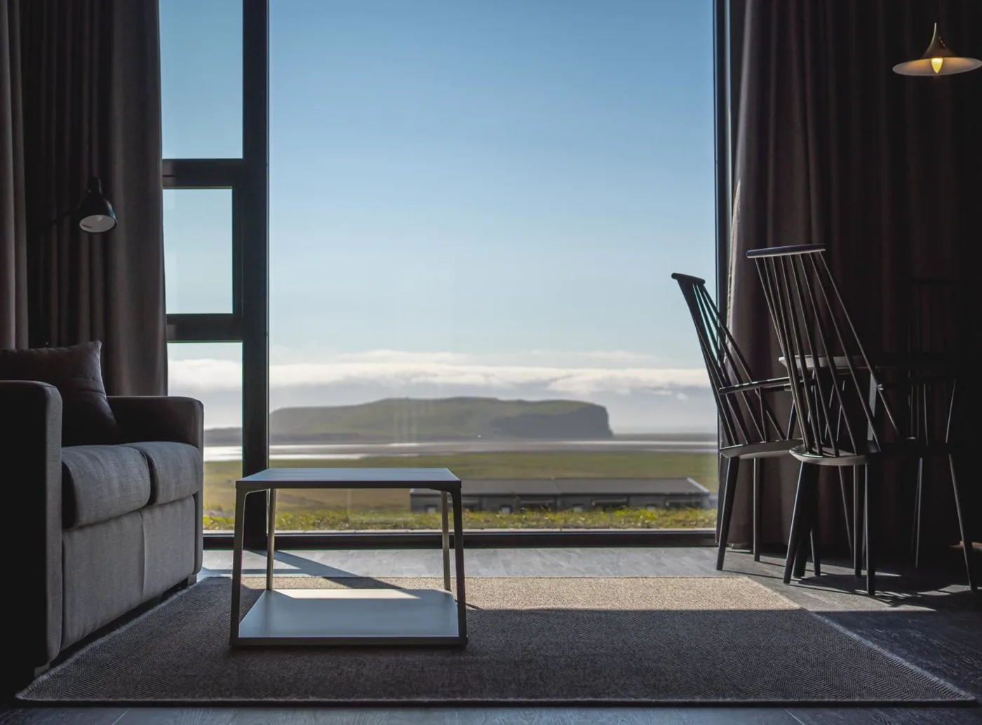 An open-plan Black Beach Suites room with dining area, kitchenette, sofa and large window
