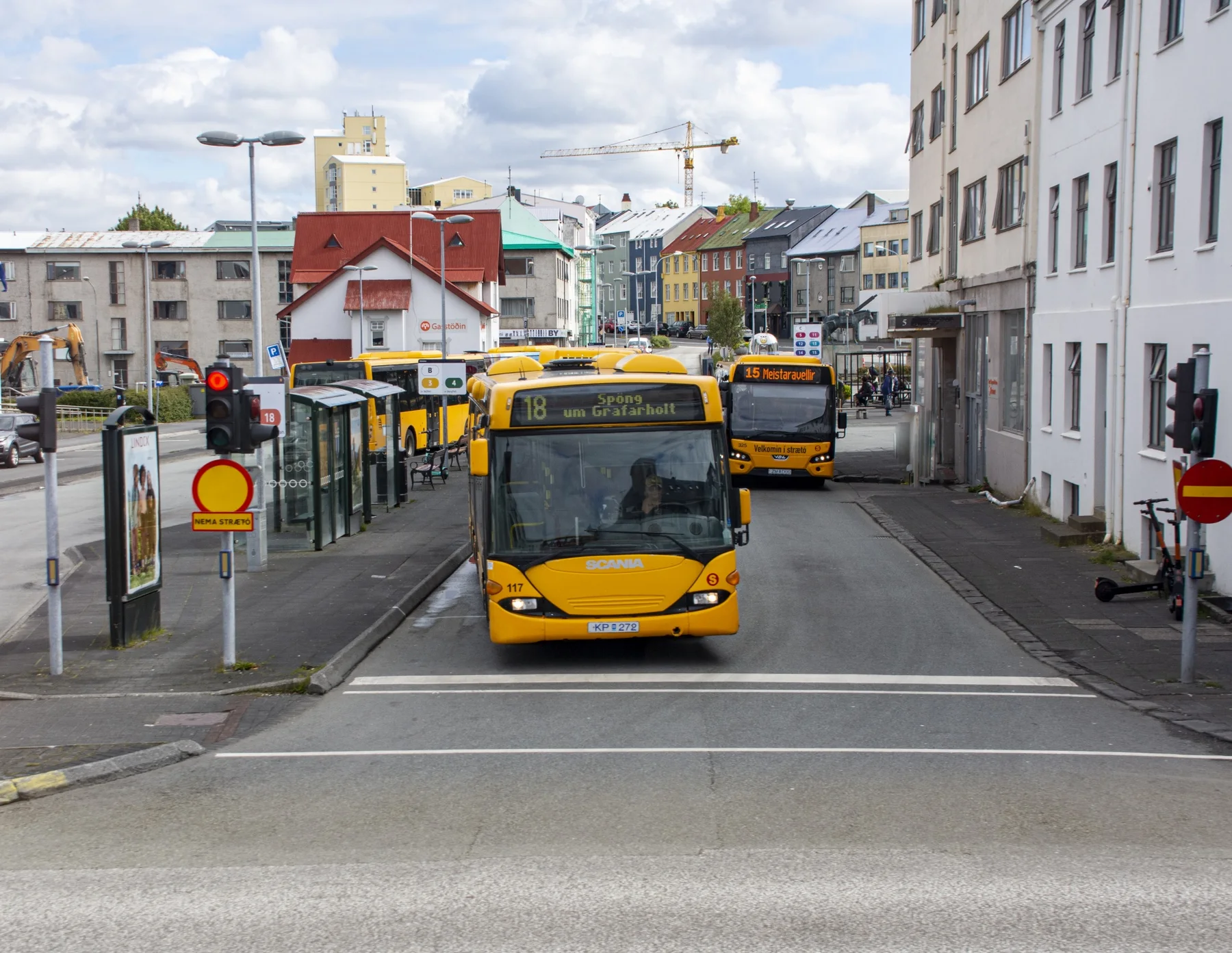 A yellow Strætó city bus at a Reykjavík street stop