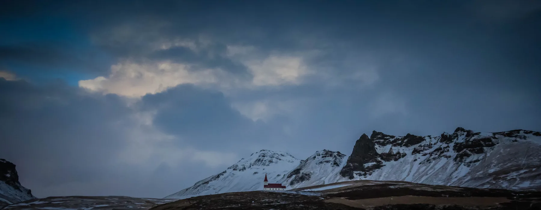 Snow-covered hills near Vík, with homes and roads below